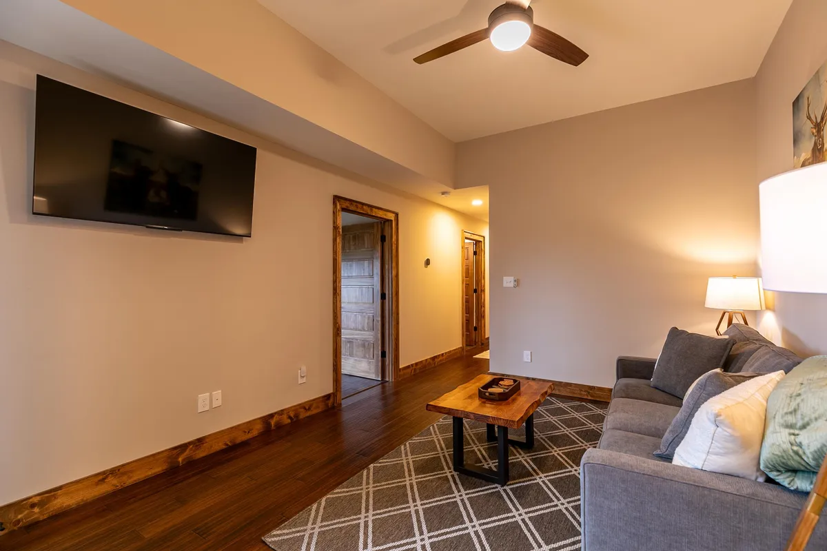 A comfortable den with a sofa, coffee table, TV, and soft lighting from a lamp—an inviting space for relaxation, movie nights, or socializing with friends and family.