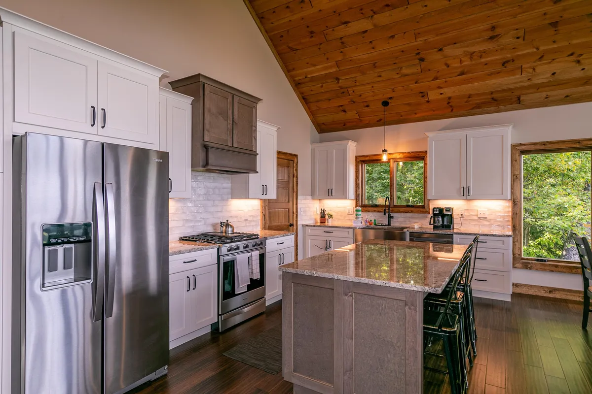 The kitchen takes center stage with its island countertop, stainless steel appliances, and windows that let in abundant natural light. The space feels modern yet inviting, perfectly suited for communal cooking, coffee mornings, and family celebrations.